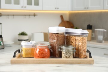 Wall Mural - Different types of cereals and legumes in containers on white marble table in kitchen