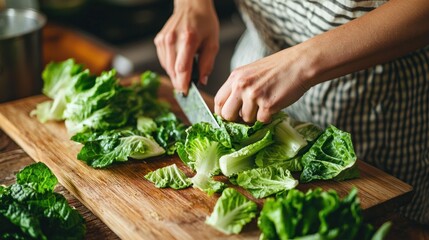 Person Chopping Green Lettuce on a Wooden Cutting Board