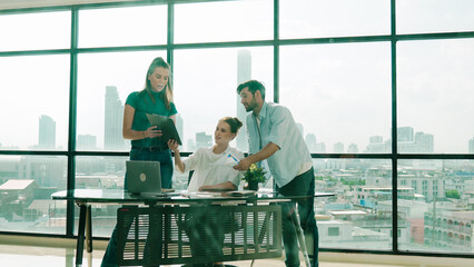 Wall Mural - Group of happy skilled businesspeople discuss, brainstorming, sharing idea, plan, strategy about financial statistic on meeting table with laptop and statistic document. Cityscape view. Tracery