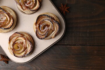 Freshly baked apple roses on wooden table, top view with space for text. Puff pastry