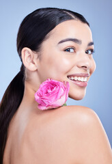 Canvas Print - Portrait, rose or woman with smile or natural beauty on blue background with flower and glow. Face, happy or girl model in studio with floral cosmetics, plants or skincare for facial results