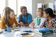 © Mediaphotos - Young female teacher explaining topic and talking to multiethnic group of students during class in school or college