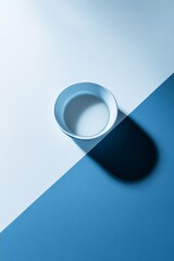 Wall Mural - A light blue bowl rests on a minimalist diagonal surface split between light blue and biege colors, creating a serene ambiance perfect for commercial use