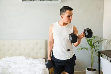 Focused young man lifting weights in bedroom, showing commitment to strength training and active lifestyle