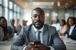 © Vera - African American businessman using mobile phone in a conference room meeting with diverse team members.