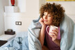 © javiindy - Relaxed lady holding cup of hot drink on bed
