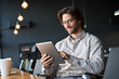 © insta_photos - Happy young European business man entrepreneur holding tad computer at work. Male professional employee worker using digital tablet fintech device sitting in office checking financial online data.