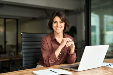 smiling hispanic young woman entrepreneur, happy female executive manager looking at camera sitting 