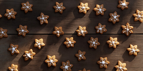 gingerbread men and snowflake-shaped cookies, each with a shadow, scattered on a rustic wooden surface