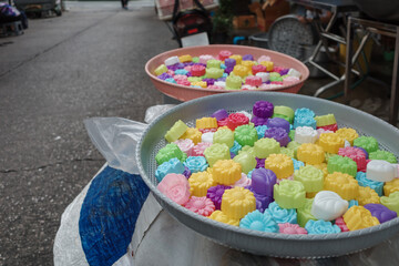 A vibrant assortment of traditional Asian sweets, beautifully arranged in round metal trays on a street market stall.