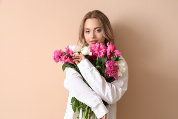 Poster - Young woman with beautiful peony flowers on beige background