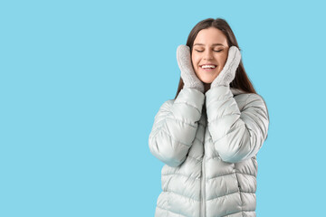 Poster - Young woman in winter clothes on blue background