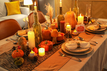 Wall Mural - Beautiful table setting with burning candles, pumpkins and greeting cards for Thanksgiving dinner at evening