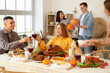 © Pixel-Shot - Group of young friends having dinner at festive table on Thanksgiving Day