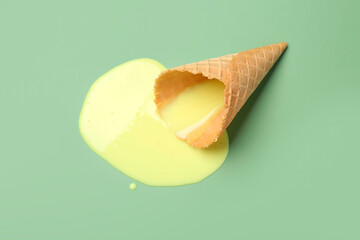 Canvas Print - Melted ice cream and wafer cone on light green background