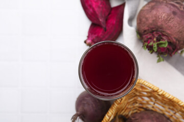 Canvas Print - Fresh beet juice in glass and ripe vegetables on white tiled table, flat lay. Space for text