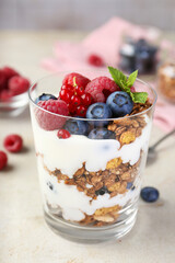 Poster - Tasty yogurt with fresh berries, granola and mint in glass on gray textured table, closeup