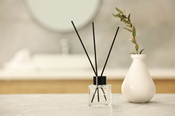 Wall Mural - Reed diffuser and vase with green twig on light grey marble table in bathroom, space for text