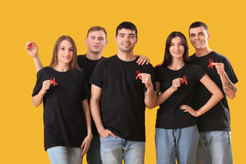 Canvas Print - Group of young people with red ribbons on yellow background. World AIDS day concept