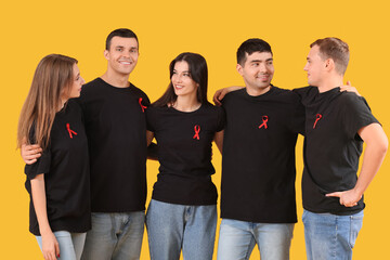 Wall Mural - Group of young people with red ribbons on yellow background. World AIDS day concept