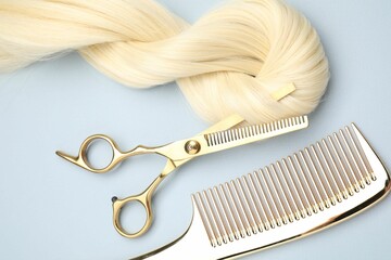 Wall Mural - Blonde hair strand, comb and professional scissors on light grey background, top view