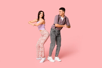 Wall Mural - Happy young couple dancing on pink background