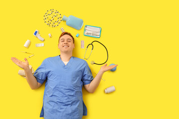 Wall Mural - Male doctor with medical supplies on yellow background, top view