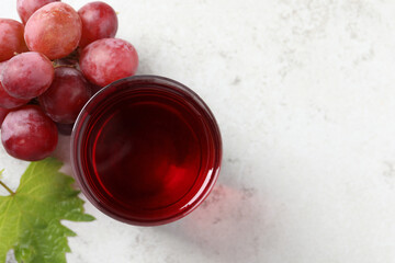 Canvas Print - Tasty grape juice in glass, leaf and berries on light table, flat lay. Space for text