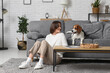 © Pixel-Shot - Young woman sitting on floor with adorable Beagle dog on grey sofa at home