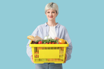 Poster - Young woman with full shopping basket on blue background