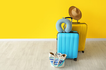 Wall Mural - Packed suitcases with neck pillow, hat and beach bag near yellow wall