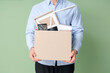 © Pixel-Shot - Fired young man holding box with personal stuff on green background, closeup