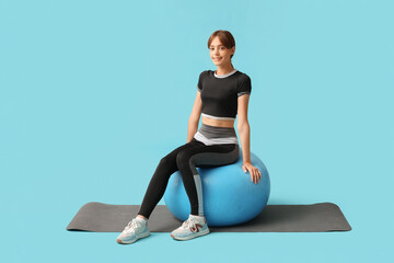 Poster - Young woman sitting on fitball against blue background