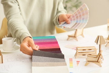 Male furniture designer with color palettes ad fabric samples working at table in office, closeup