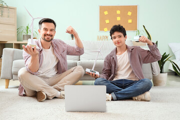 Poster - Teenage boy and his father with wind turbine models showing muscles at home