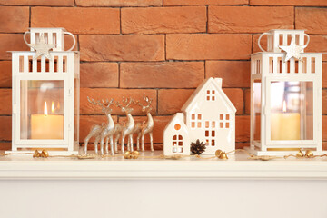 Poster - House shaped candle holders with lanterns and Christmas decor on fireplace near brick wall