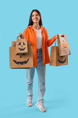 Canvas Print - Young woman with shopping bags on blue background. Halloween celebration