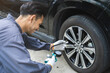 © KMPZZZ - Auto mechanic man checking tire measure air pressure, measurement with gauge for car tyre, mechanic maintenance repair, fix car flat tire with psi pump for safety at vehicle garage, service station