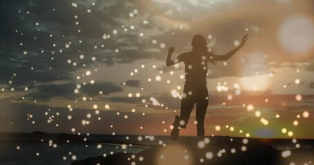 Poster - Silhouette of person dancing over glowing bokeh lights animation at sunset