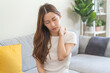 © KMPZZZ - Pain body muscles stiff problem, asian young woman, girl painful with back, neck ache from work hand holding massaging rubbing shoulder hurt, sore sitting on couch at home. Health care and medicine.