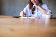 © Farknot Architect - Closeup image of a woman writing on a notebook with mobile phone and coffee cup on wooden table