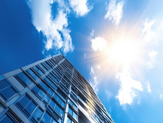 A modern skyscraper reaching toward a blue sky, illuminated by bright sunlight and contrasting clouds, symbolizing urban architecture.