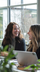 Wall Mural - Two women are sitting at a table, laughing and smiling