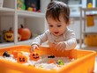 © phurinee - Toddler Playing with Pumpkin Toys in Sensory Bin