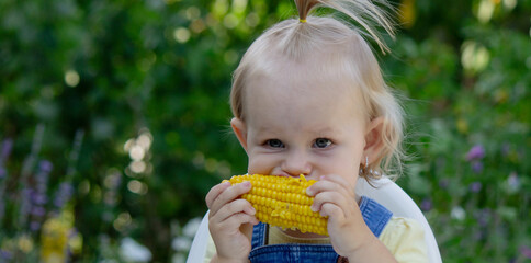 Poster - little girl eats corn. Selective focus