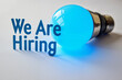 © MOTOKO Stock - Illuminated Blue Light Bulb with 'We Are Hiring' Banner: Innovative Recruitment Visual for Job Postings and HR Campaigns