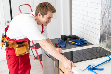 craftsman installs hob in kitchen. Household Appliance Installation Services Concept.