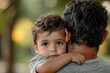 © Lumina Frame - Latin American dad carries his 3 year old son in his arms in the park. Close up shot. Family and father's day concept, Generative AI