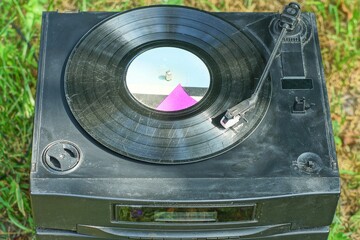 one black vinyl music with tracks old retro record in the player stands outside during the day