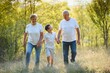 © Serhii - Grandson, grandfather and grandmother sitting on grass having fun outdoors in park at sunset